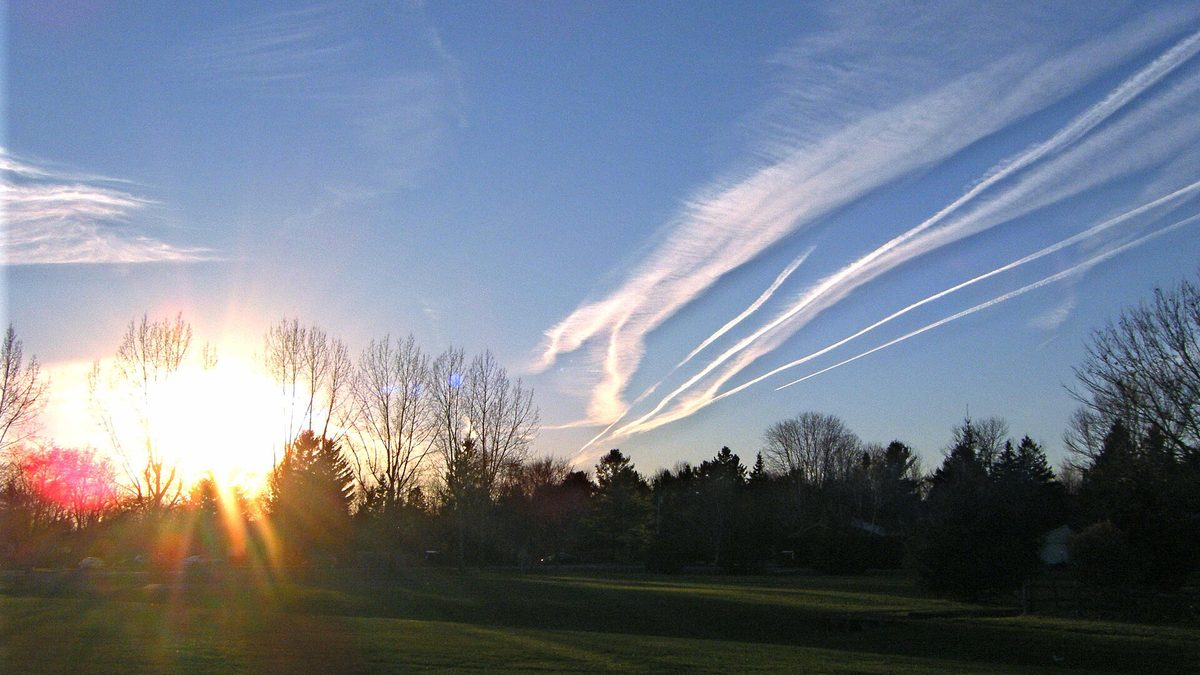 Sunset with contrails over open fields at the edge of Manotick